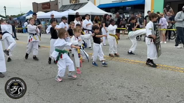 Students in white gi mid-kick at the Tucker Day Parade