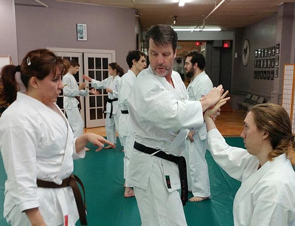 Adults practicing a wrist-lock on the mat